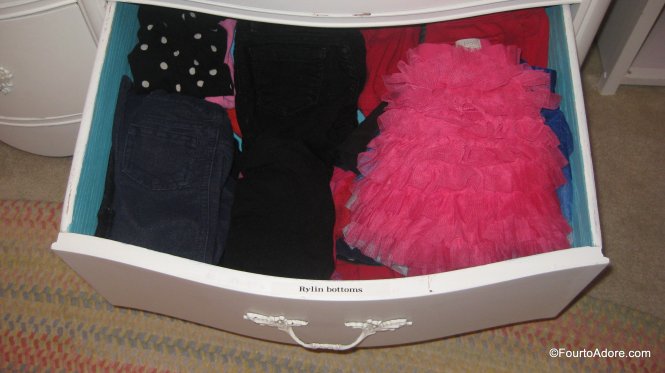the inside of the girls dresser is labled designating whose clothes are whose